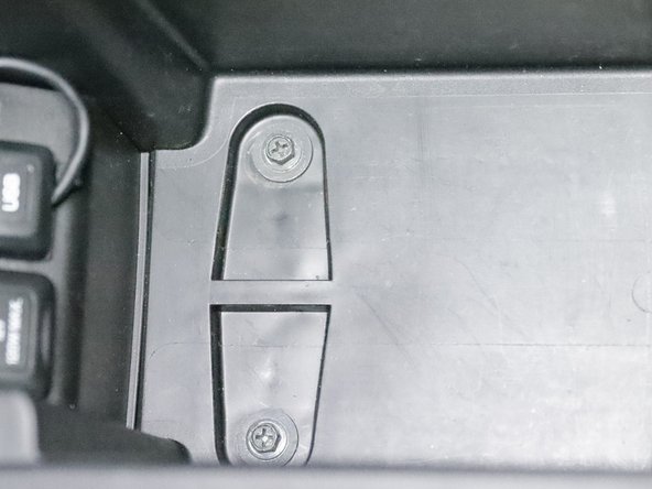 Inside of the center console armrest, there are two screws located under the felt liner. Remove them.