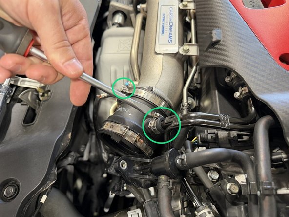 Loosen the coupler clamp at the turbo inlet, pull the coupler off, and remove the smaller hose clamp. Both are circled in the first image.