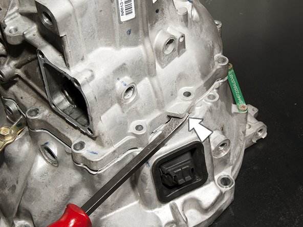 Using a pry bar, gently pry the two halves of the transmission case apart. Lift and remove the upper half of the case. Before moving on, use a razor to scrape off the HondaBond that was sealing the joint where the two halves of the case met.