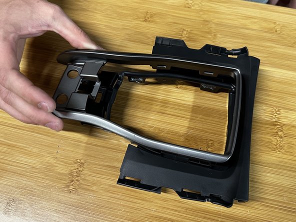 You can now remove the trim ring from the console cover. Depress the tabs and push the ring out.