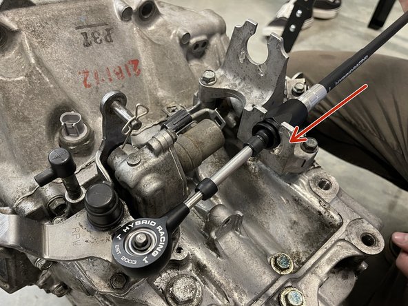 Then, install the cable through the transmission bracket. Secure with the supplied C clip.