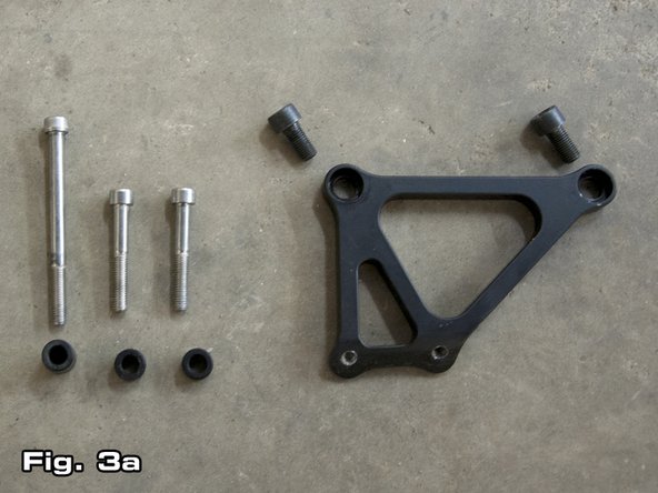 To reinstall the alternator, first the supplied alternator bracket (as shown on the right in Figure 3a) must be installed. The bracket bolts up to the same two (2) holes the original A/C bracket bolted to (see Figure 3b). Use the 2 supplied black M10x1.25 bolts.