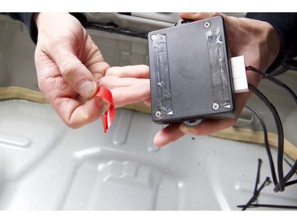 On the back, remove the tape backing and install the controller under the trunk latch.
