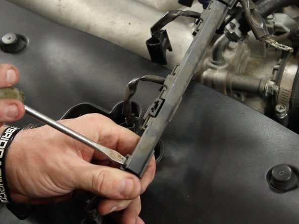 Using a flat tip screw driver or pick, remove the plastic wire harness cover.