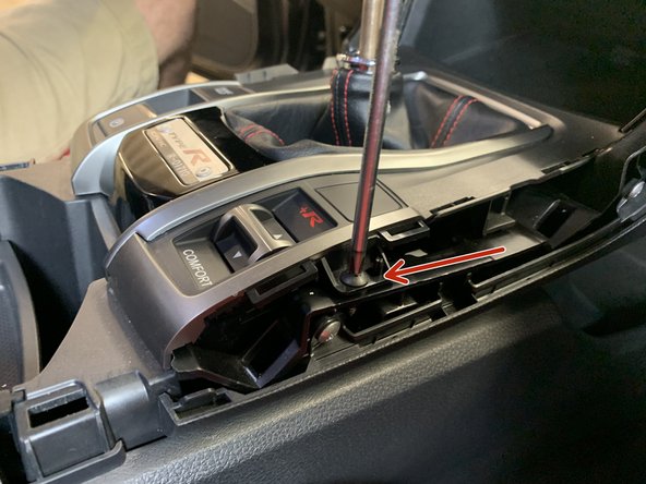 Using a #2 phillips screwdriver, unscrew the two screws that hold the shift boot cover.
