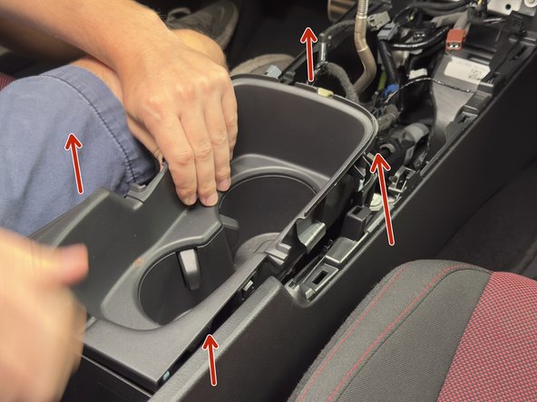 Pull upward on the cup holder section to unclip it. Remove it and set aside.
