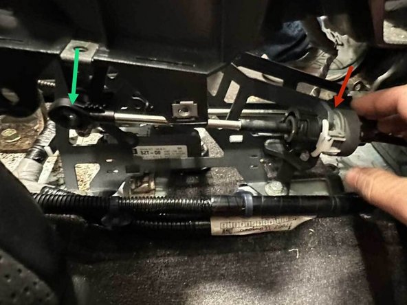 To reconnect the shifter cable, rotate the black collar counter-clockwise and slide the cable housing straight into the shifter bracket until it is fully seated. The spring will pull the collar tight when you let go. Finish by pressing the white locking tab flush so the collar locks securely in place.