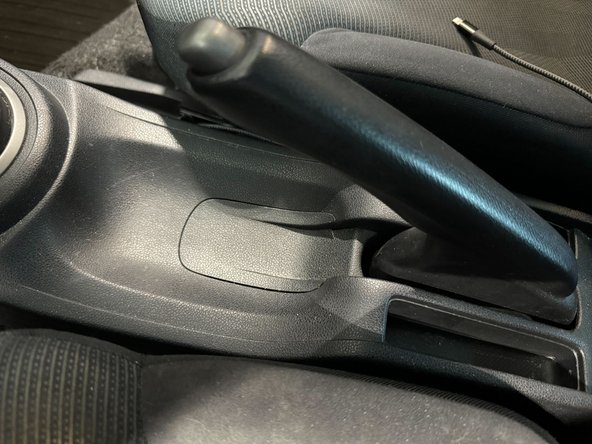 Pull up on the small panel underneath the handbrake.