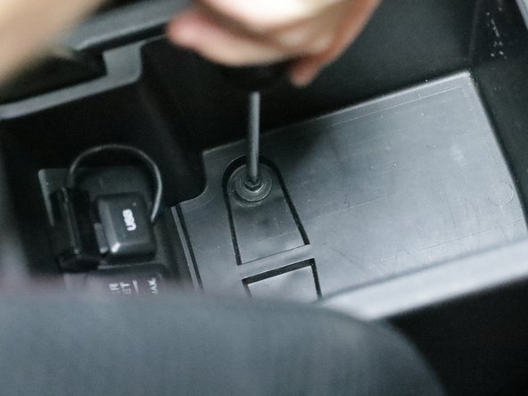 Inside of the center console armrest, there are two screws located under the felt liner. Remove them.