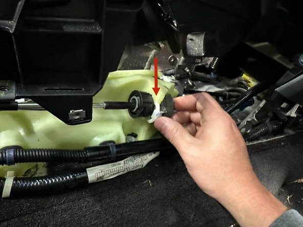 The shifter cable is secured to the shifter by a twist-lock collar. Pull the white locking tab straight out, then rotate the black collar counter-clockwise until the internal spring bottoms out (it’s stiff, so expect a few firm turns). Once the collar stops, slide the cable housing straight out of the shifter plastic.