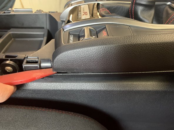 Use a plastic panel tool to pry the upper console section. Once it pops up, grab the upper section and pull it towards you.