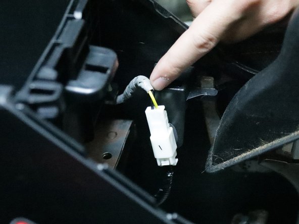 Unplug the white connector and prepare to remove the console from the car.