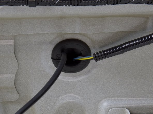 Use a pair of scissors or knife and cut a slit into the factory grommet. Feed the wire through the slit and re-install the grommet in place.