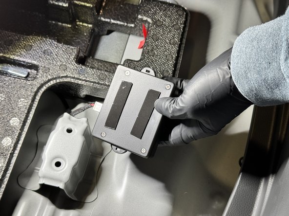 On the back, remove the tape backing and install the controller under the trunk latch.