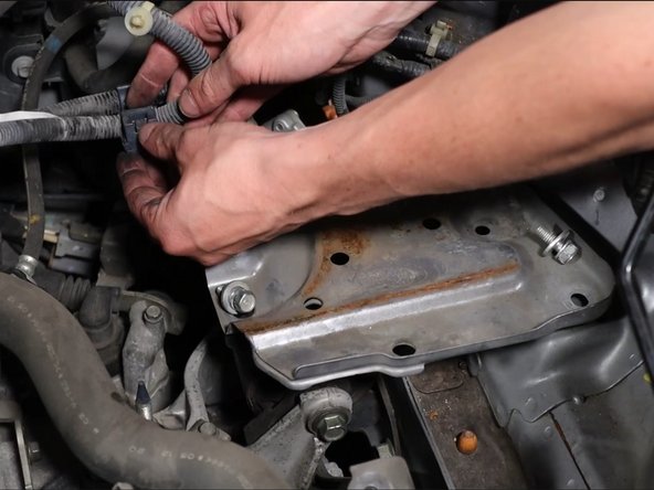 Unclip the wiring harness connector and remove the harness from the battery tray bracket.