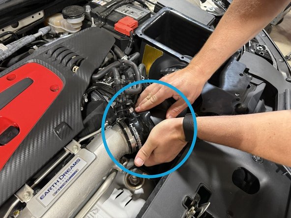 After lowering the airbox into the bay onto the factory mounting points, work the intake tube into the coupler.