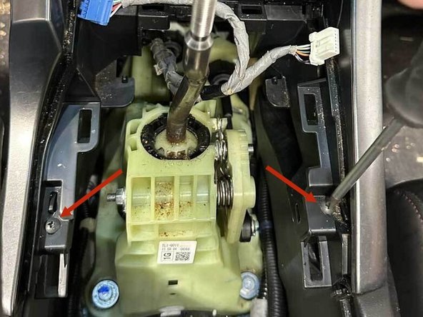 Remove the two Phillips screws securing the console side trims; remove both.