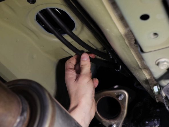 Then bend the cables upwards and slide them through the hole in the floor. You can now attach the bracket and slide the rubber grommet in place.