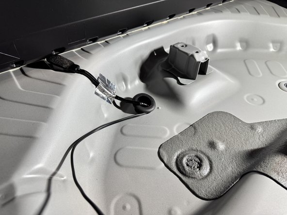 Located the factory floor grommet that was removed and cut a small slit into the edge.