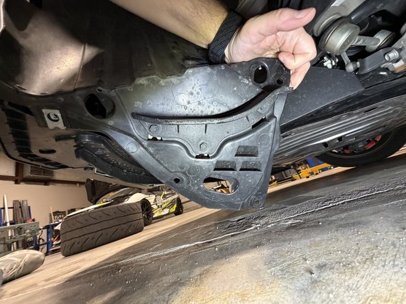 Remove the splash shield fasteners under the front of the car and drop the cover.