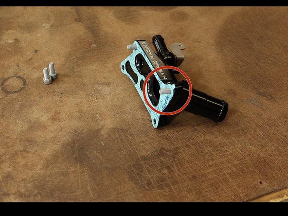 Install the gasket with the tab on the top. Take two of the included bolts and stick them through the housing.