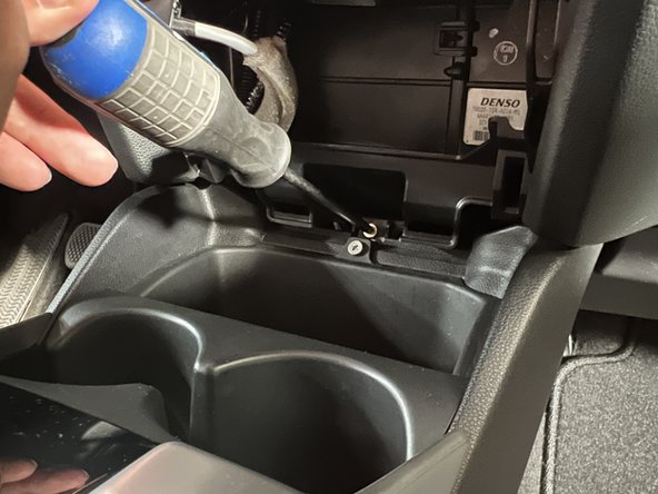 Remove the mounting screw and prepare to remove the console from the car.