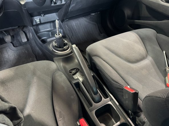 Lower the console and feed the shifter rod through shift boot.