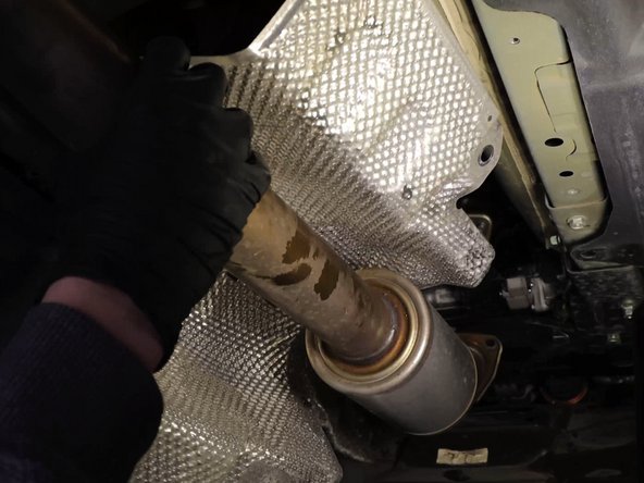 Remove the heat shield bolts and slide it out of the way, exposing the shifter cables.