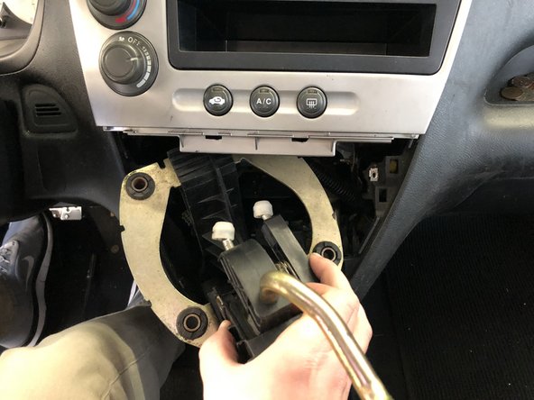 Remove the shifter assembly by pulling the center dash section outwards and upwards. Hold it out of the way to give you more room to pull the shifter out.