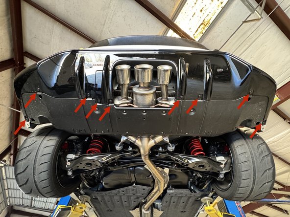 At the rear of the car, remove the plastic clips that hold the lower bumper valence in place.