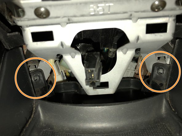 Remove the final two screws holding the top section of the center console in place.