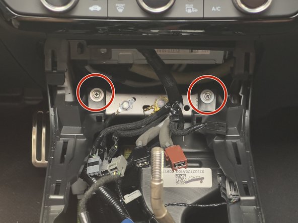 Remove the two 10mm mounting bolts on the front section of the console.