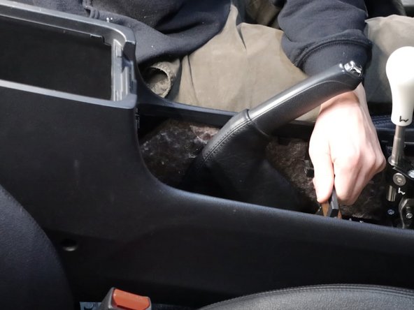 Unhook the ebrake boot from the console and slide the entire console backwards a few inches.