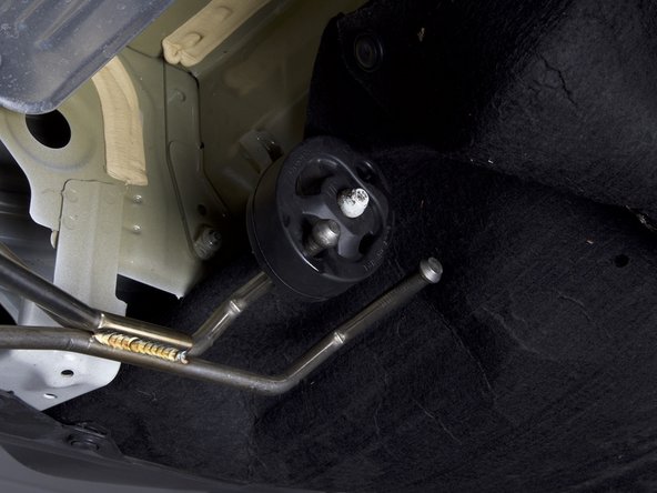 We suggest just installing one hanger through the bushings at a time. Once you have one hanger in each bushing, you can rotate the rubber and get the other one through.