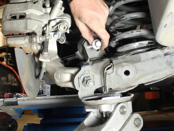 Remove the bolt and slowly lower the jack to separate the lower control arm completely away from the strut.