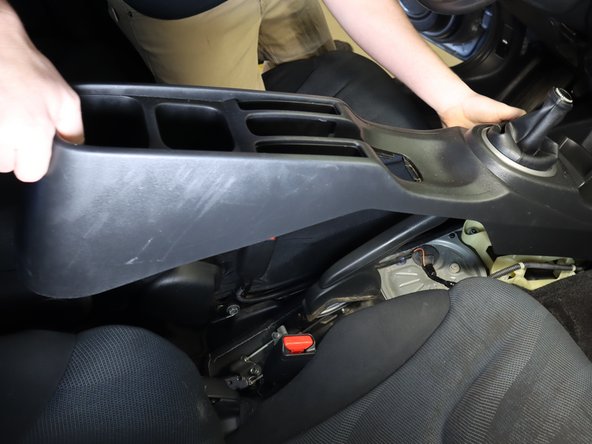 With the e-brake pulled up, slide the console backwards and tilt the rear up.