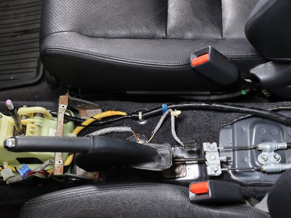 Lift the console up from the rear and angle it around the shifter and e-brake handle. Remove it from the car and set it aside.