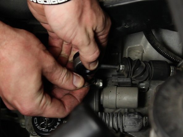 Open the retaining clip and carefully slide it into the groove on the backside of the cable bushing.