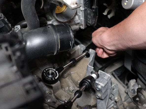 In the engine bay, install the shifter cables through the transmission bracket.