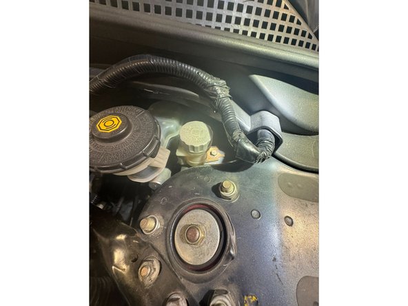 Remove the x1 M6x1.0 bolt mounting reservoir to strut tower. Use a 10mm socket and extension.