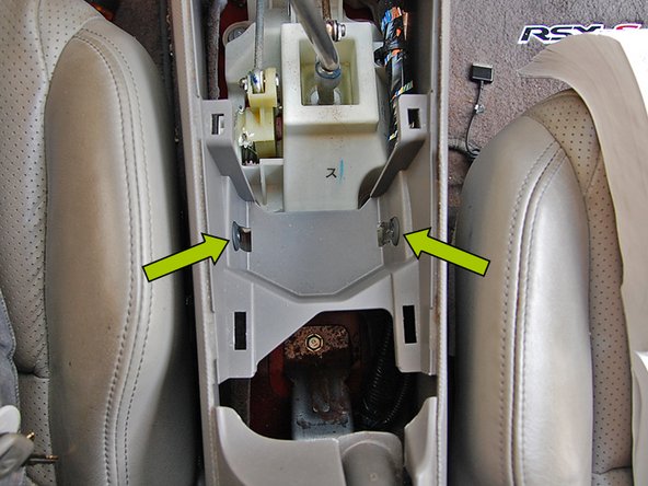 Again, using the same Phillips head screw driver remove the next set of screws just behind the shifter.