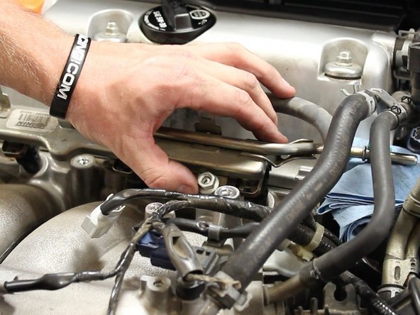 With both hands, carefully pull away the fuel rail from the manifold to remove.