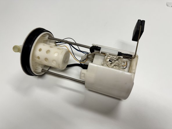 Remove the fuel pump assembly from the vehicle. Be sure to work in a clean, well-ventilated area away from flames. There will be gasoline inside the pump.