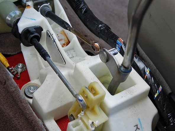 Use a small flat head screwdriver and bend the cotter pins straight, remove both cotter pins securing the cable end links to the shifter and pull them off the shifter.