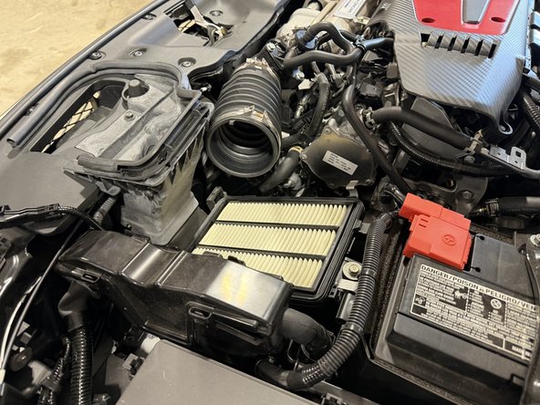 Remove the air intake tube (the front duct) from the cover and pull it out of the car. It is held by soft tabs, so just pull and it comes out pretty easily. The third photo shows it fully removed.
