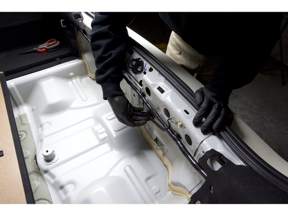 On the rear bulkhead, locate the rubber grommet in the center. Use your fingers or a flat-tipped pry tool and pull the grommet free.