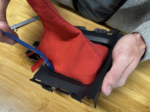 Use a trim tool, pick or flat screw driver and push the fabric through the trim. Make sure the boot is spaced evenly.