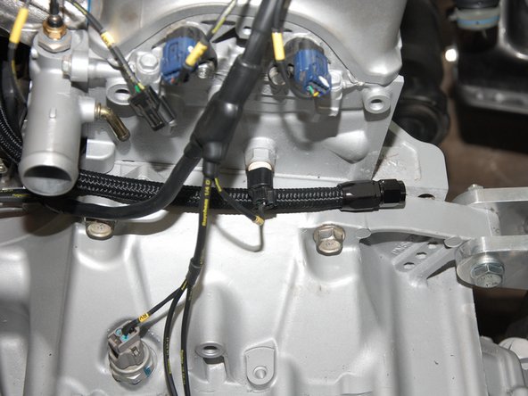 Route line (A) between the intake manifold runners and along the side of the cylinder head.