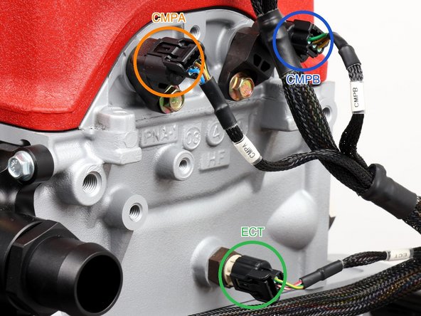 Plug in cam sensor A (labeled CMPA, orange ring) on that same end face, tucked up under the valve cover lip.