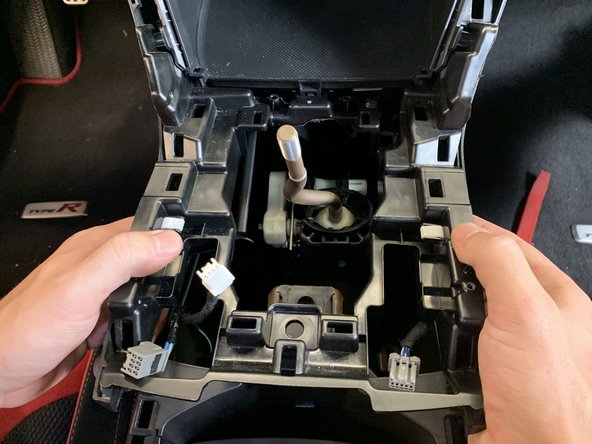 Use your hands and pop the sides of the console up. Once it is free, lift upwards and remove it completely.